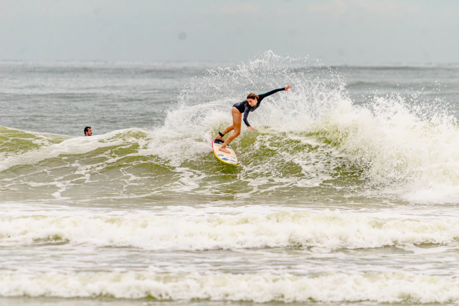 Ana Aguiar surfando e realizando manobra no topo da onda